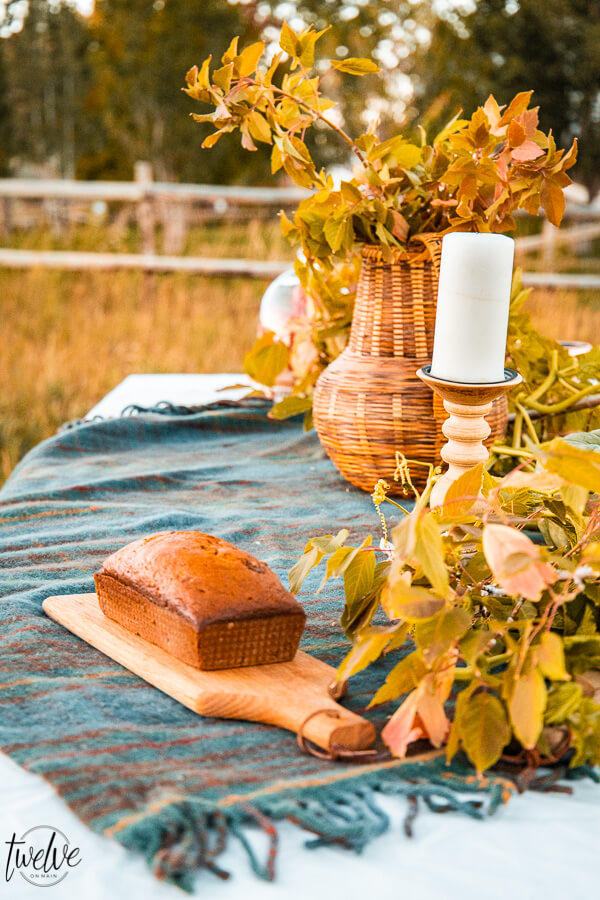 Outdoor fall entertaining, with simple fall table decor, set outside with a tall grass field as a backdrop.