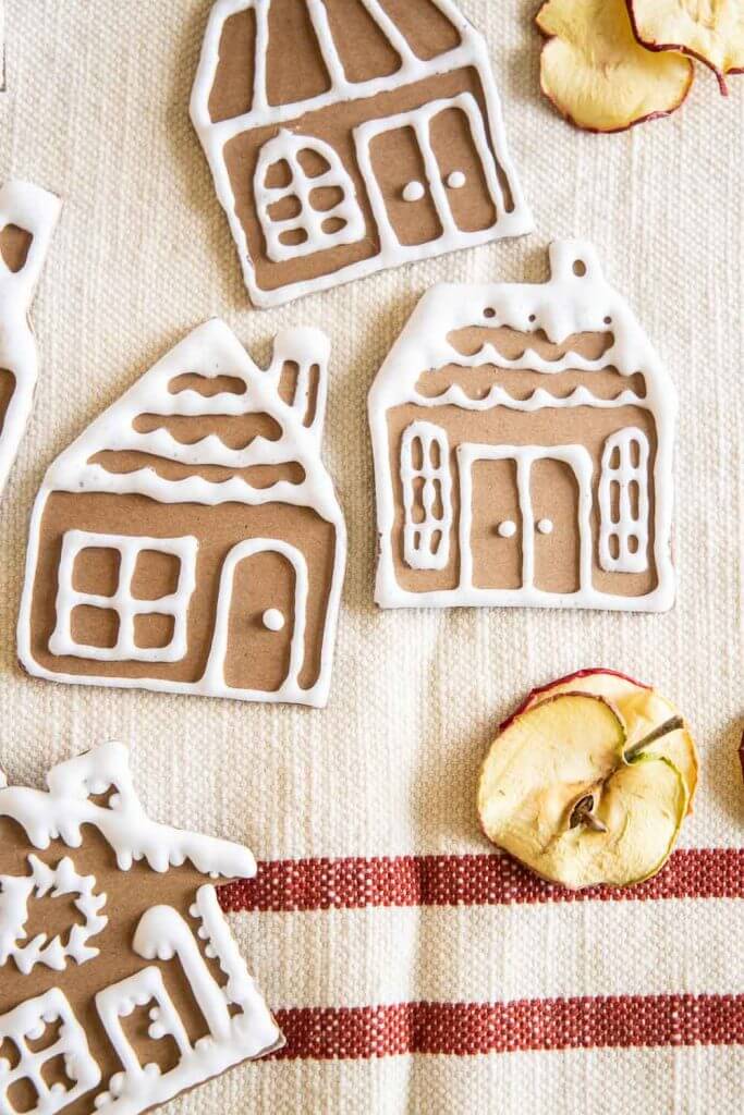Make these easy gingerbread house ornaments using craft or chipboard, a Cricut Machine, homemade puff paint and more!