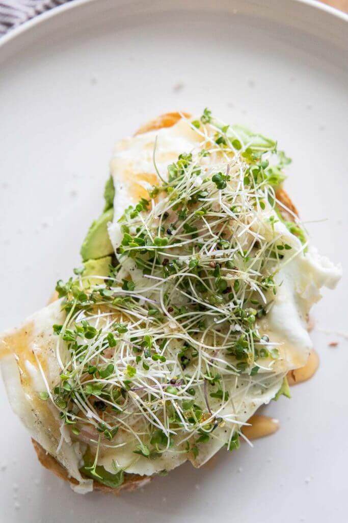 This hearty and healthy sourdough breakfast sandwich with eggs, avocado, microgreens, hot honey and sea salt is the perfect balanced breakfast. It is so full of flavor and is a perfectly balanced meal.